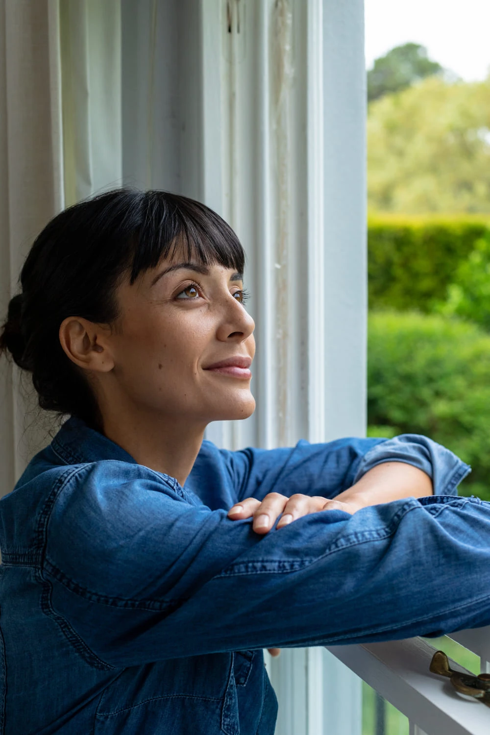 una mujer sonriente mirando por la ventana